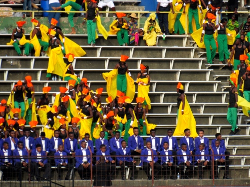 The purple blazers are invaded by enthusiastic dancers in green and yellow, topped with orange.